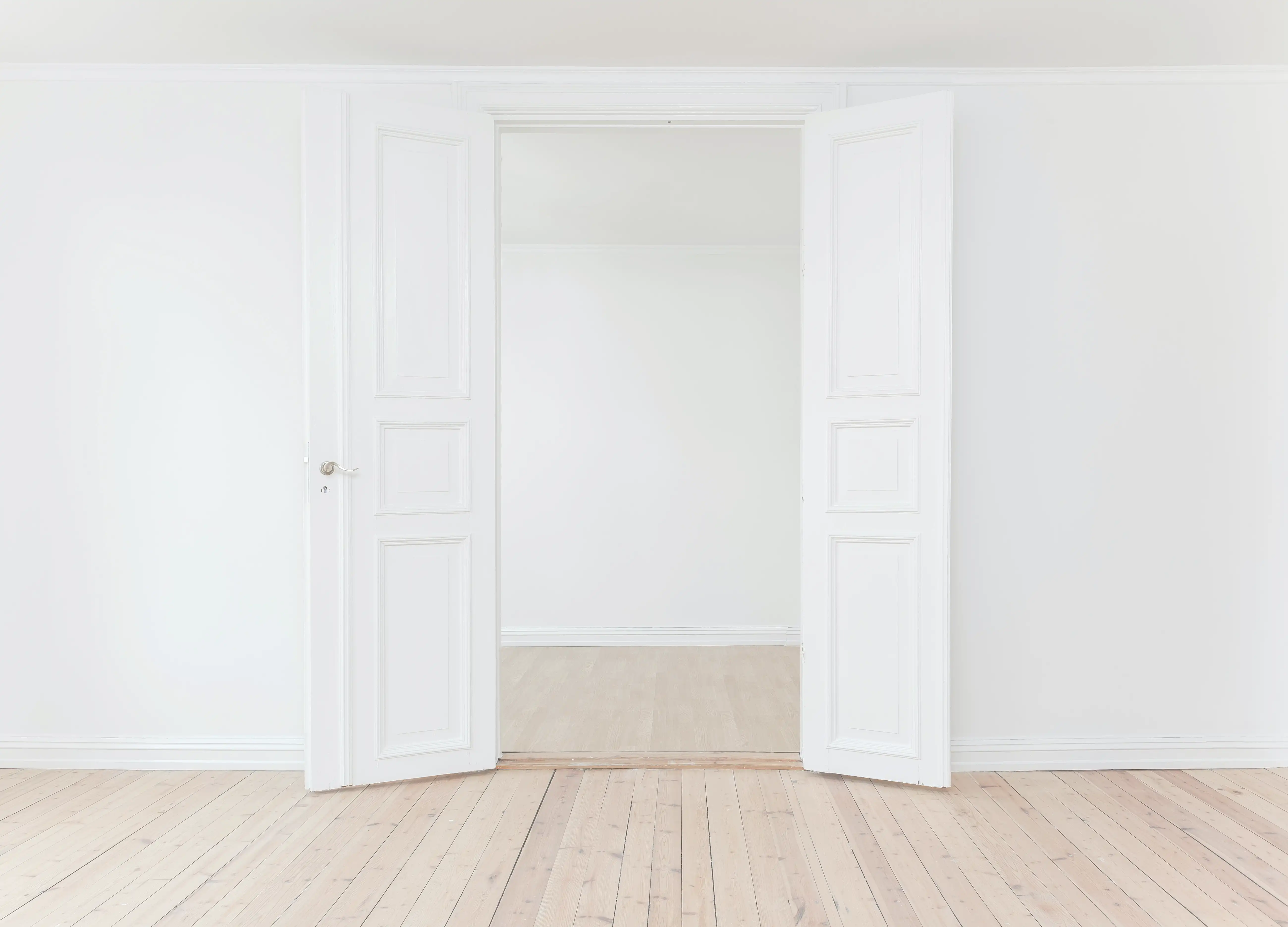 A photo of a bright, wood-floored double door entrance.